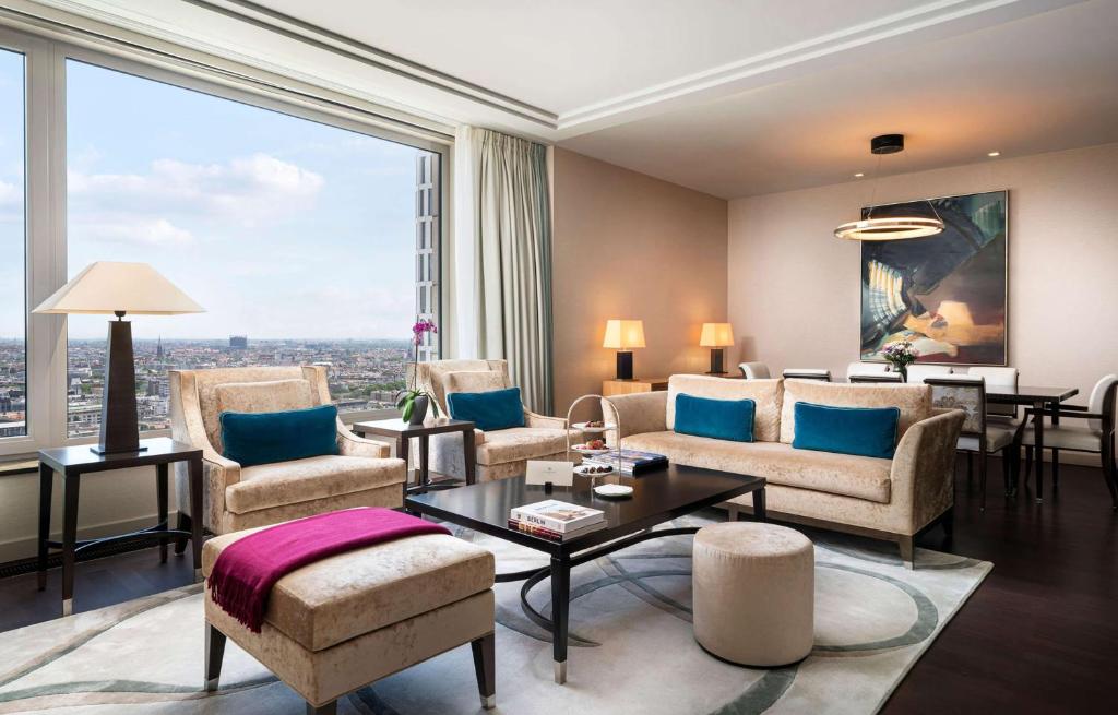 a living room with furniture and a large window at Waldorf Astoria Berlin in Berlin