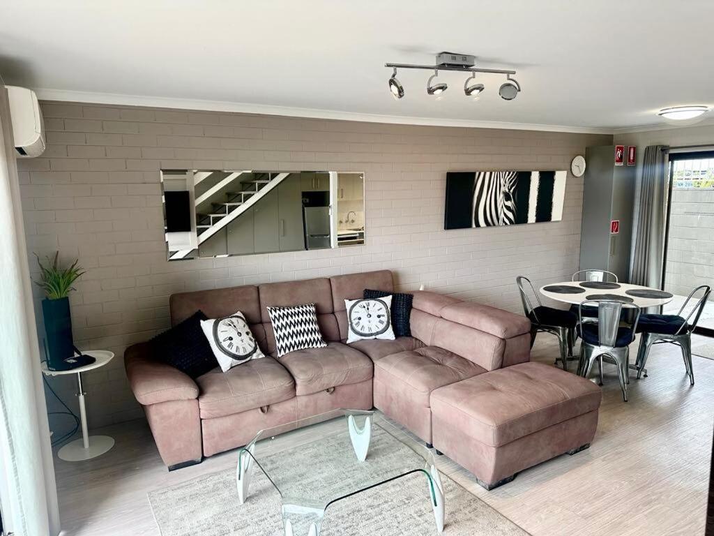 a living room with a brown couch and a table at 2 Bedroom 2 level apartment Hydra Unit 3 in Merimbula