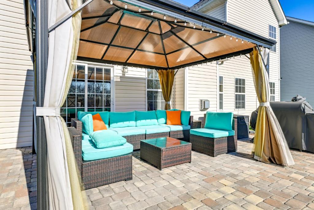 une pergola avec un canapé et des chaises sur une terrasse dans l'établissement 6 Mi to Charlotte Motor Speedway Home with Fire Pit, à Concord