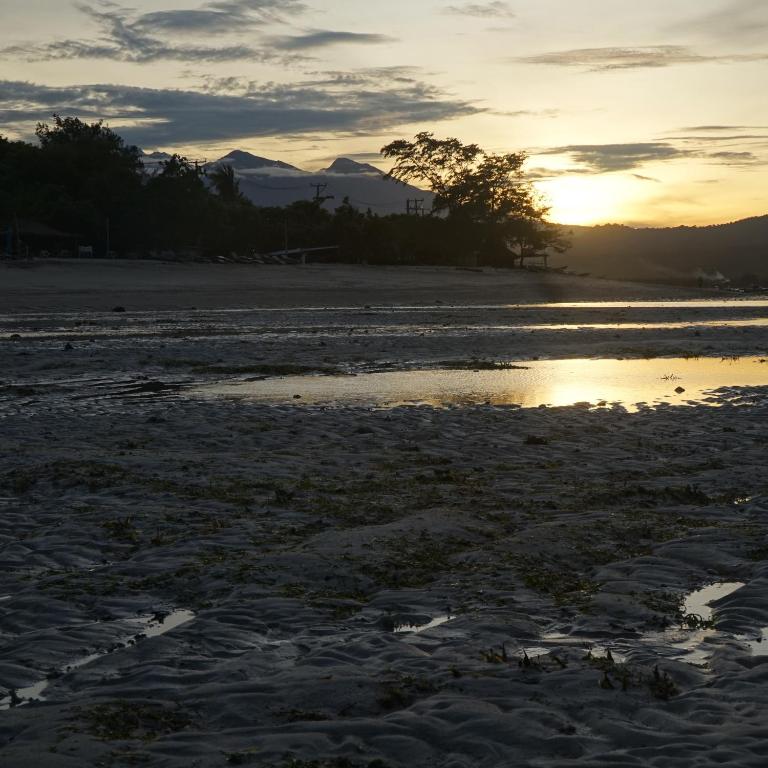 a sunset on a beach with a body of water at Mola2 Resort Gili Air in Gili Islands
