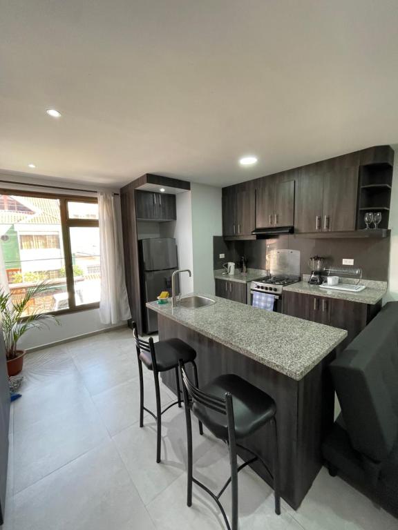 una cucina con un bancone e alcune sedie di Lindo Departamento excelente ubicación a Cuenca