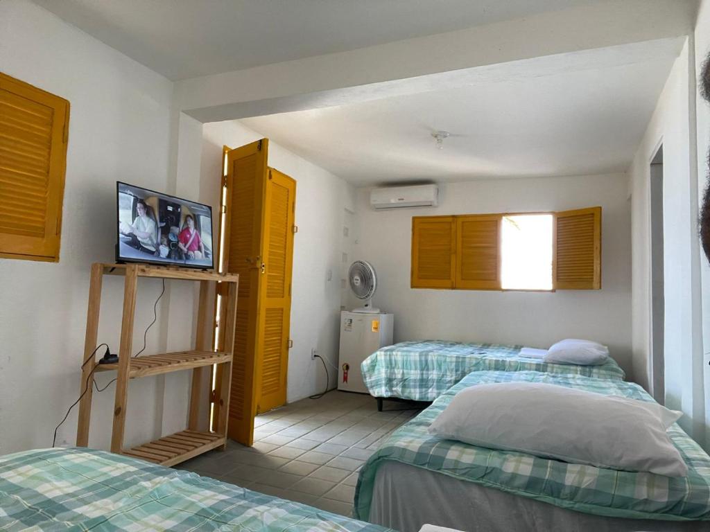 a room with two beds and a tv in it at Flats a Beira-Mar Praia Di Campina in Rio Tinto