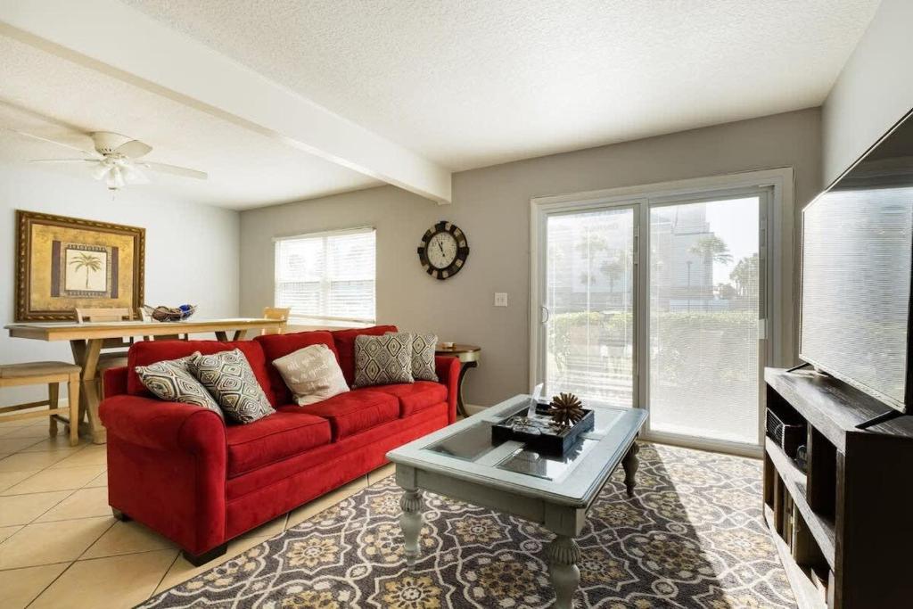 a living room with a red couch and a table at Tides Beach Paradise - Two Apartments Combined in Jacksonville Beach