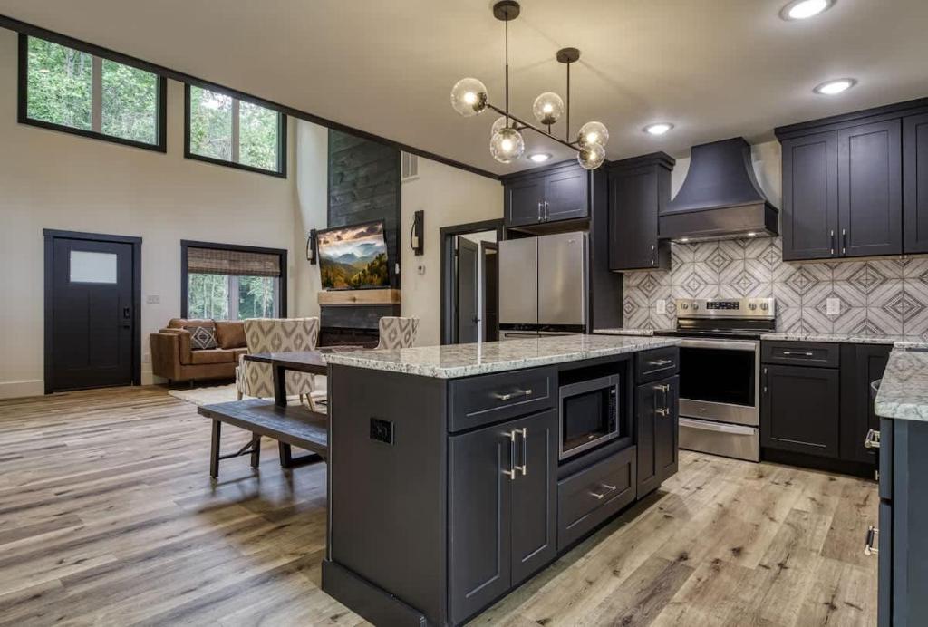 a large kitchen with black cabinets and a table at Arise in the Glades in Gatlinburg
