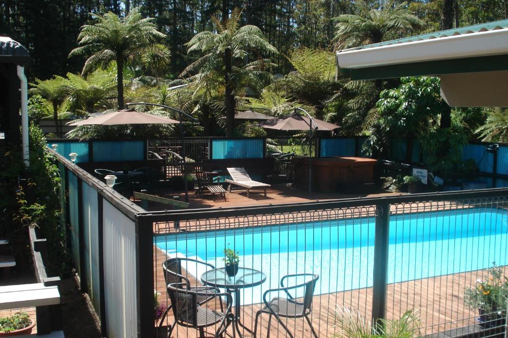 a swimming pool with a table and chairs next to it at Woodlands Motel in Kerikeri