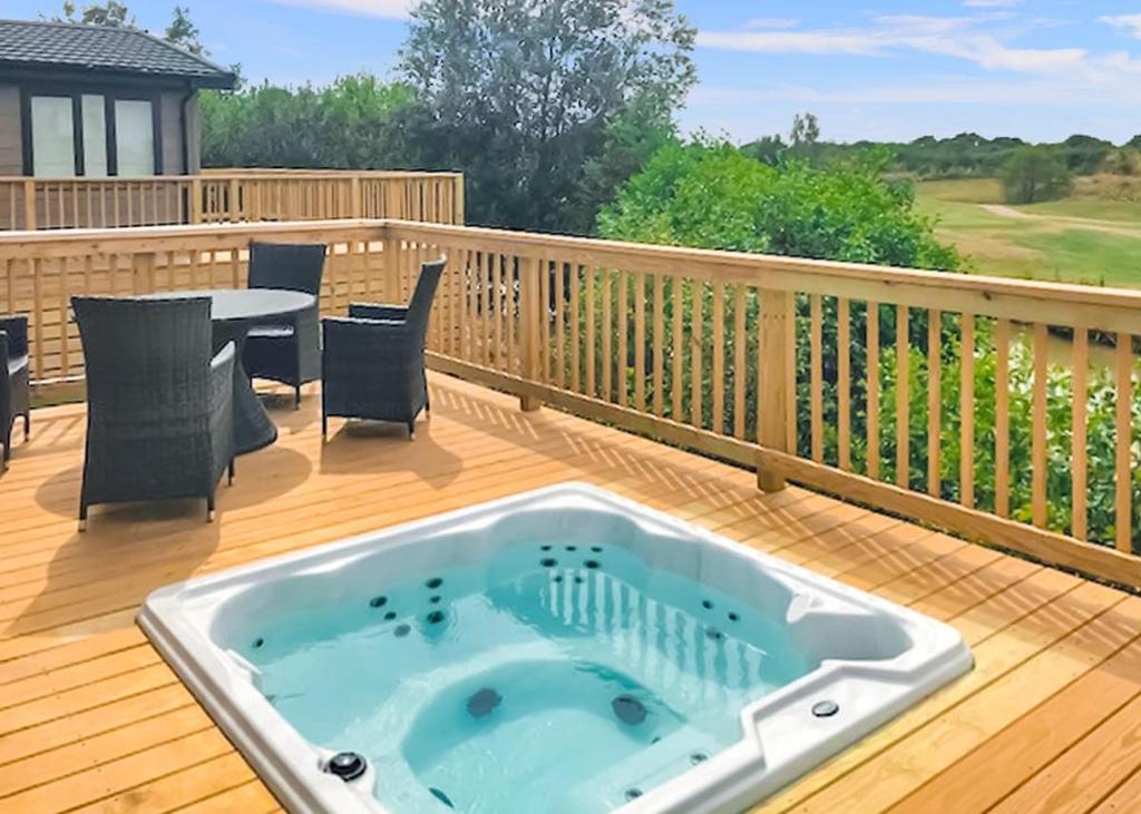 a hot tub on a deck with a table and chairs at Kingswood Golf Lodges in Thorne