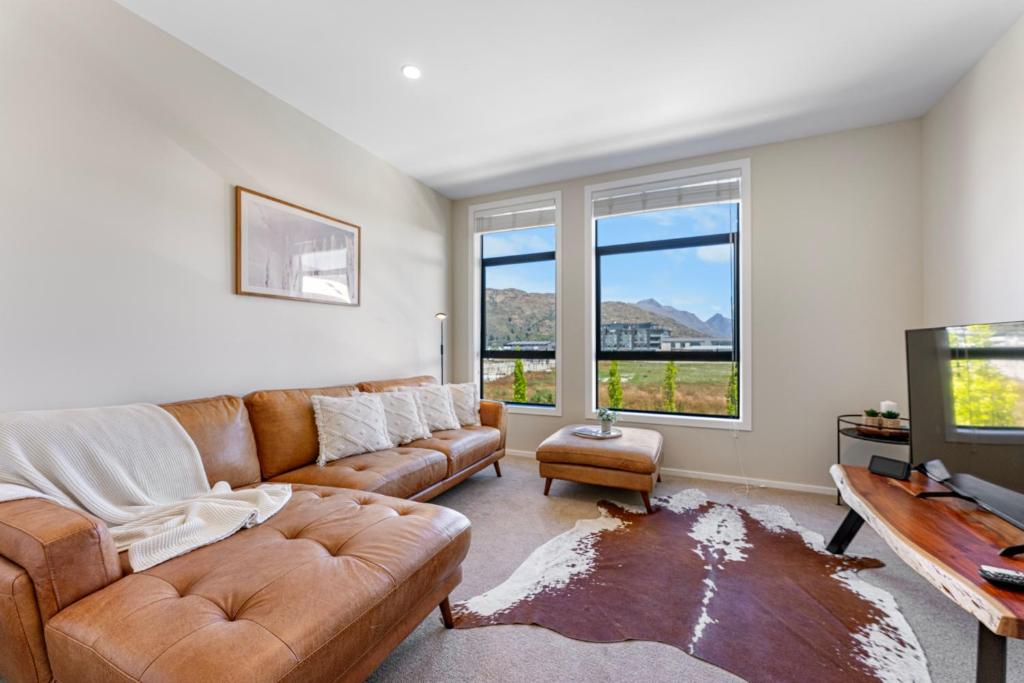 uma sala de estar com um sofá e uma TV em New 4BRs Townhouse, Walk to Shops & Cafes, 5mins to Airport, 30mins to Ski em Queenstown
