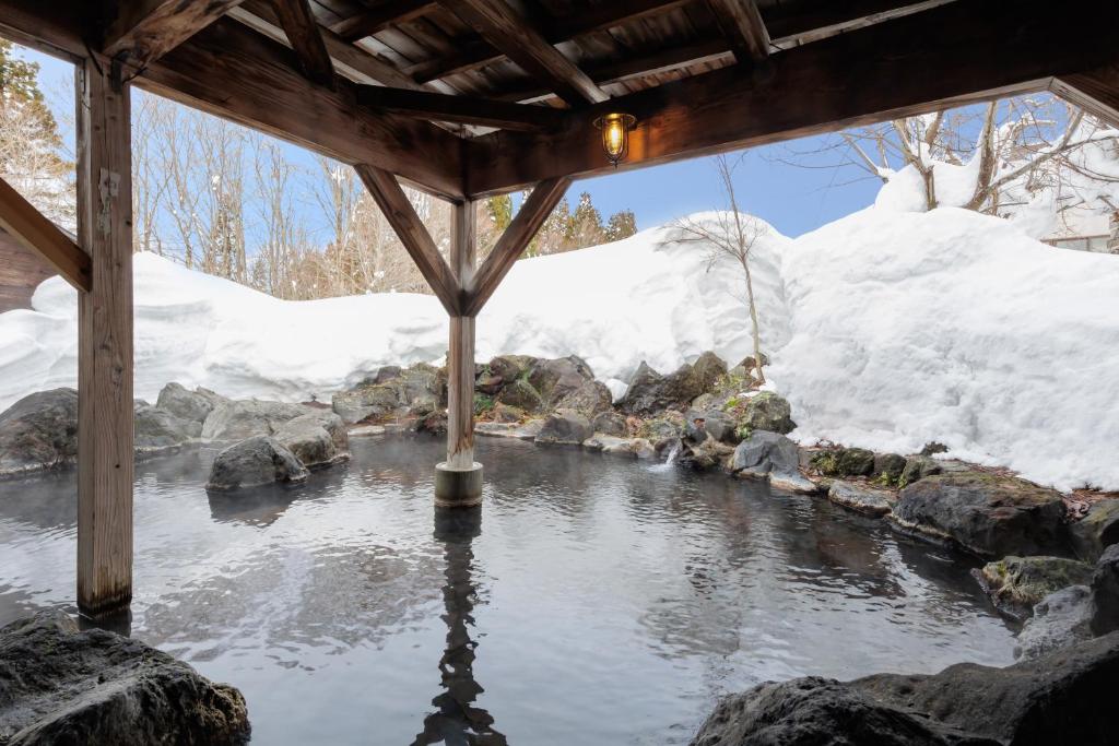 a view of a pond with snow in the background at KAMENOI HOTEL Tazawako in Senboku