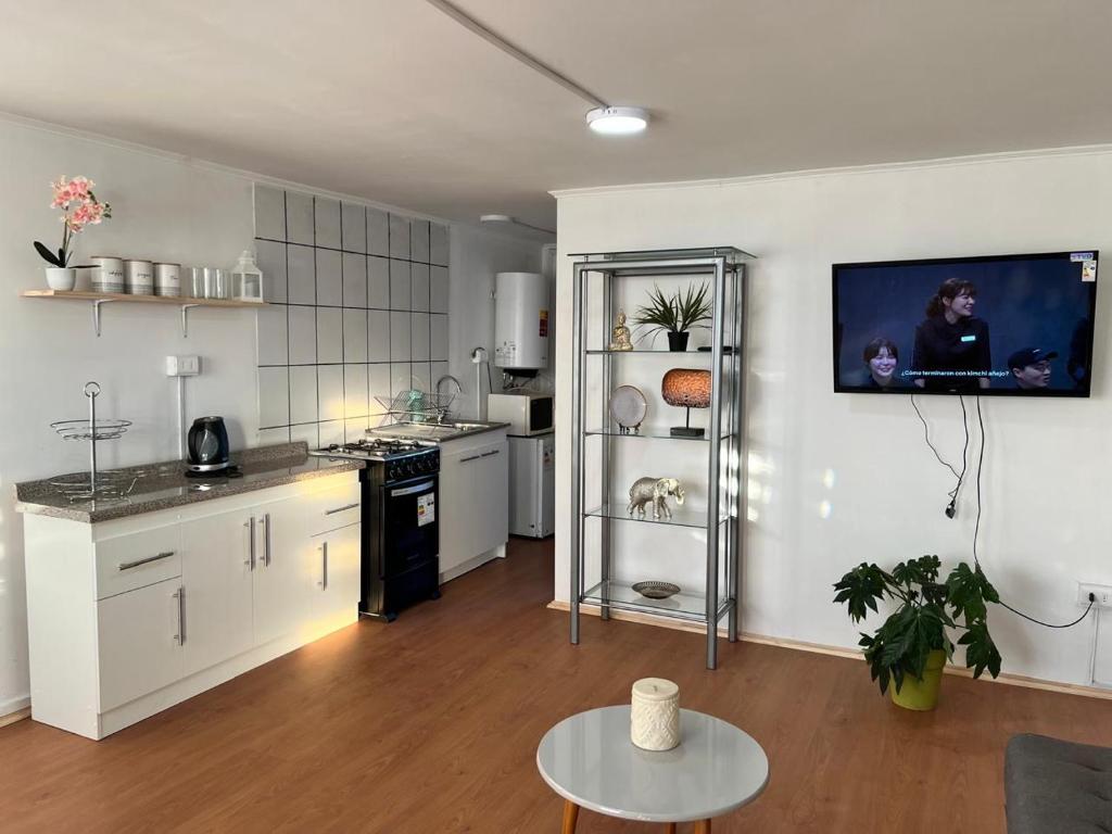 a kitchen with white cabinets and a table in a room at Cómodo Departamento en Puerto Montt in Puerto Montt