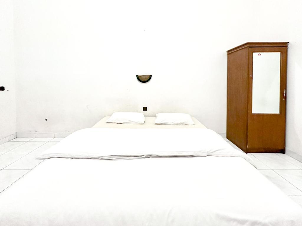TimuranHotel Dewi Sri Prawirotaman RedPartner的白色卧室配有床和木柜