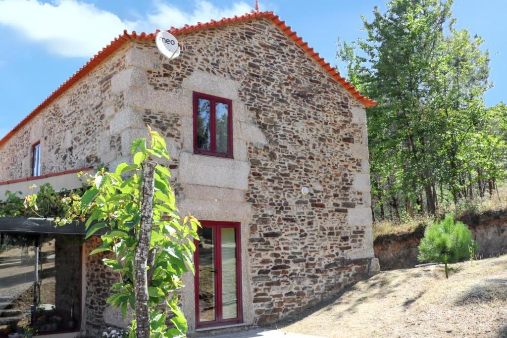 Una pequeña casa de piedra con una puerta roja. en Cozy House in Seia with Fireplace, en Faia