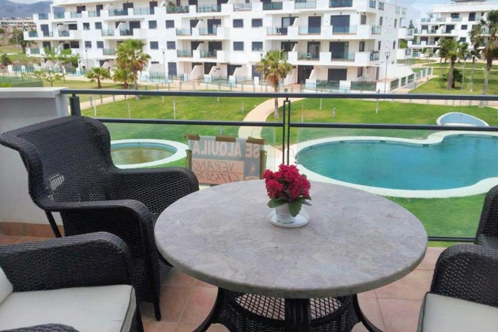 stół z wazonem z kwiatami na balkonie w obiekcie Comfortable Apartment in Almería with Shared Pool - 72 m² w mieście Retamar