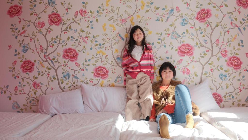 茅野市にあるGuesthouse HOALOHA 4 SEASONSの二人の女の子がベッドの上に座っている