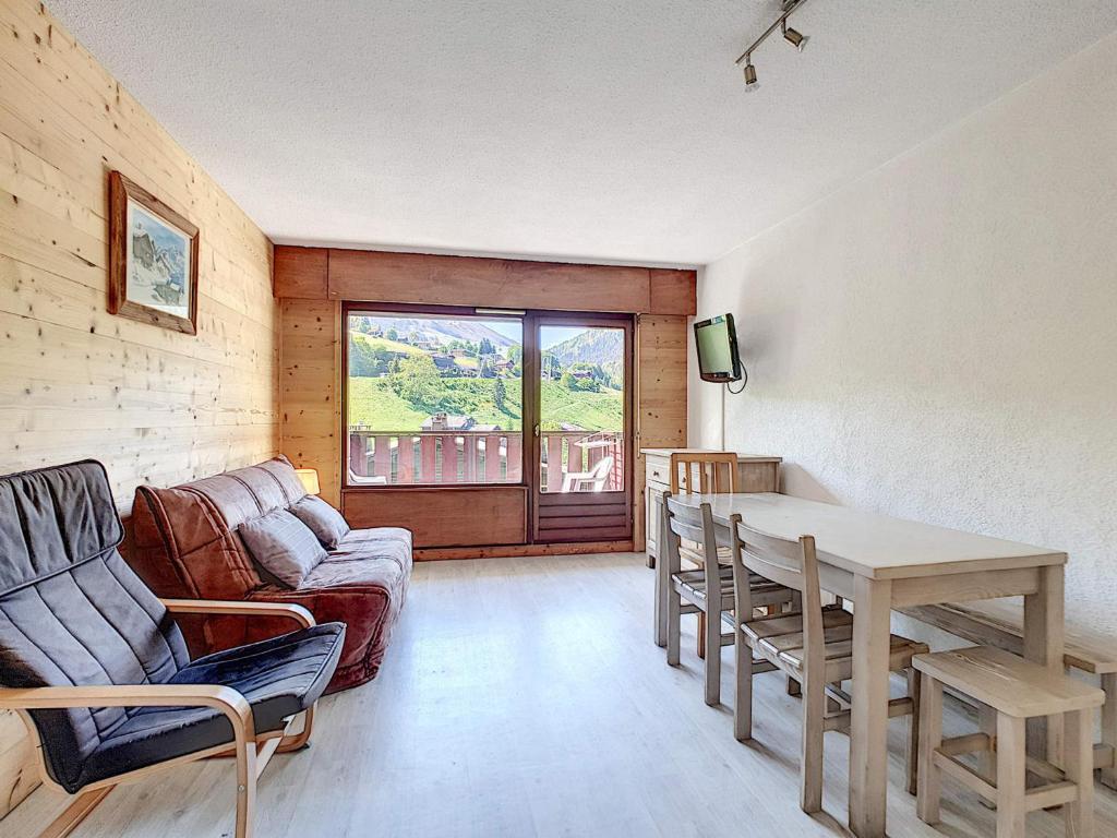 un salon avec une table et un canapé dans l'établissement Appartement cosy avec balcon Sud et wifi, animaux admis - FR-1-818-41, à La Clusaz