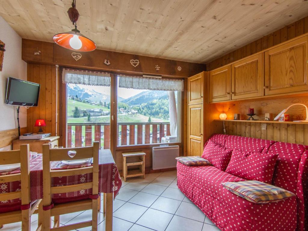 un salon avec un canapé rouge et une table dans l'établissement Studio cosy avec balcon et wifi, animaux admis - La Clusaz - FR-1-818-84, à La Clusaz