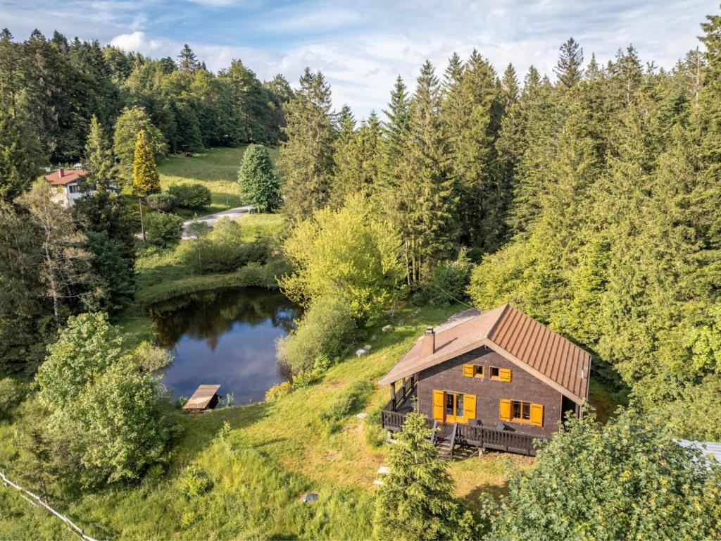 une vue de tête sur une maison sur une colline avec un étang dans l'établissement Chalet moderne avec cheminée et animaux bienvenus proche de Gérardmer - FR-1-589-778, à Sapois