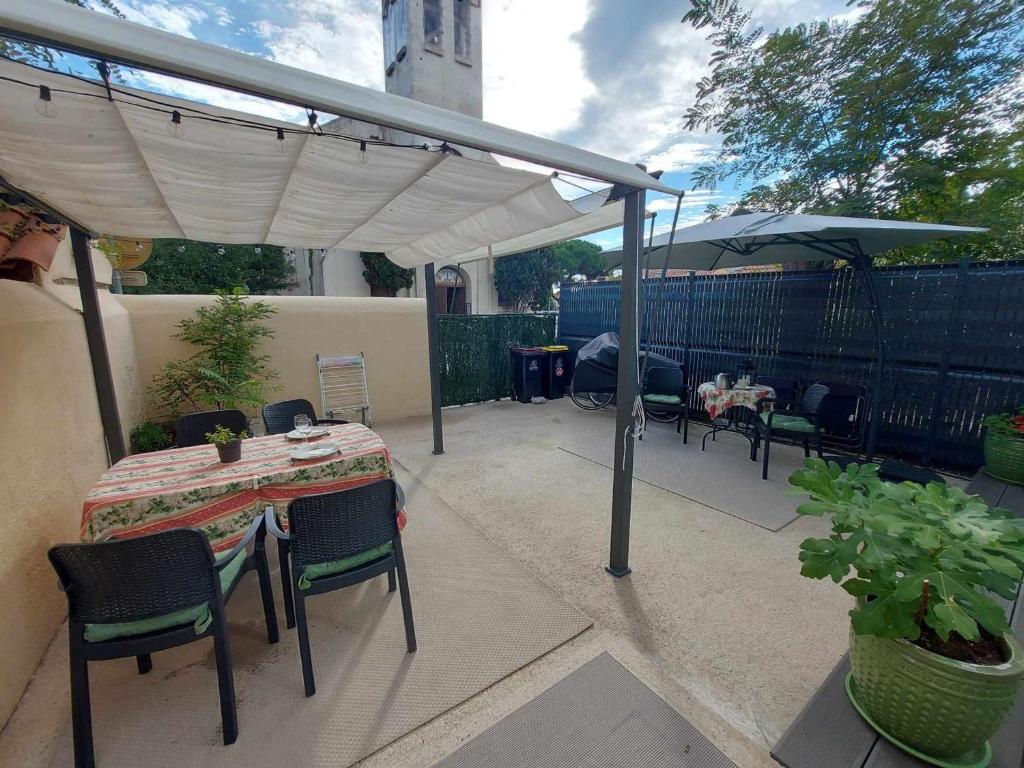 un patio avec une table, des chaises et un parasol dans l'établissement Appartement 3 pièces avec terrasse, clim et WIFI, proche plage et commerces - FR-1-423-312, au Grau-dʼAgde