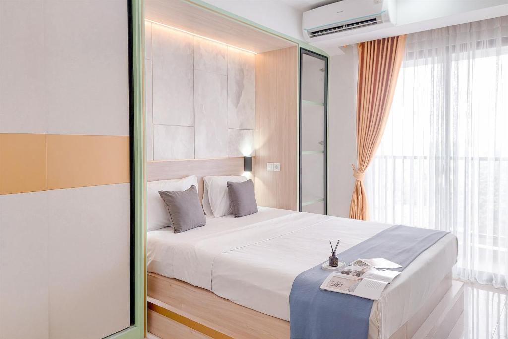 una stanza d'albergo con un letto e uno specchio di Homey and Comfort Stay Studio Apartment at Anwa Residence By Travelio a Tangerang