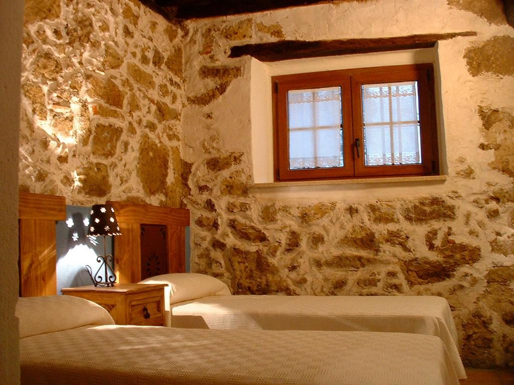 a bedroom with three beds and a window at Apartamentos Rurales La Antigua Fonda in Candelario