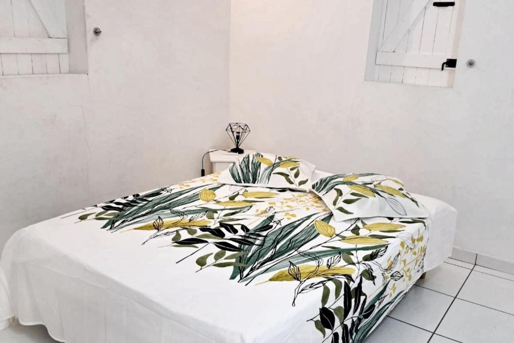 a bedroom with a bed with a tropical blanket at Maison confortable à Le Moule avec piscine partagée in Le Moule