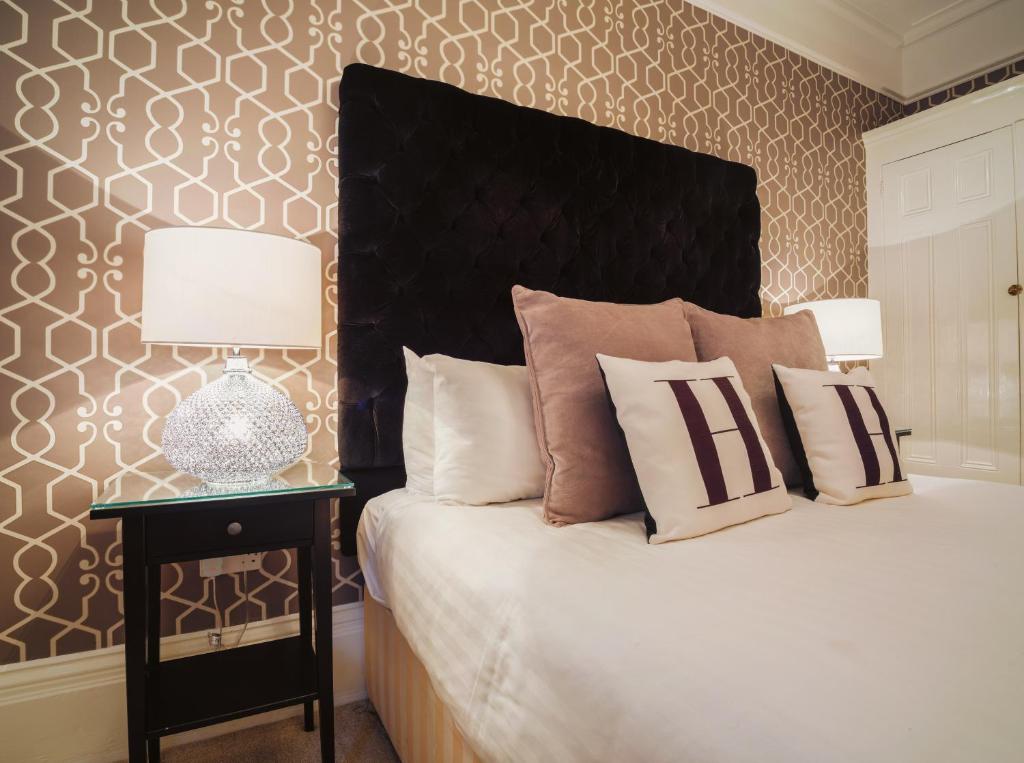 a bedroom with a bed with a black headboard and a table at Stattons Boutique Hotel & Restaurant in Portsmouth