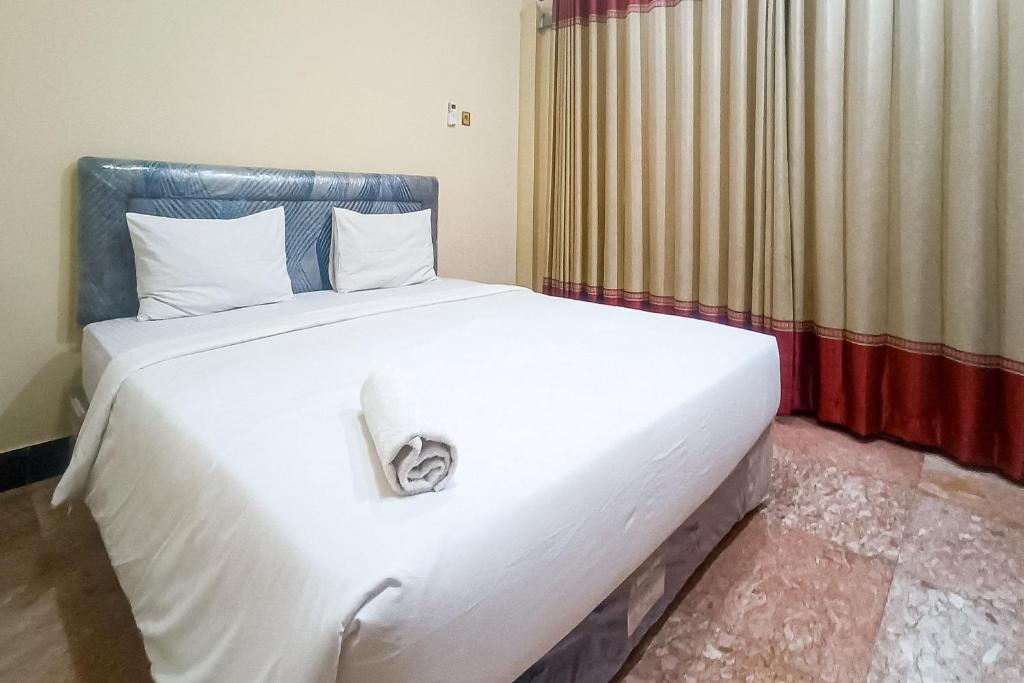 a large white bed in a room with a window at RedDoorz at Senaz Guesthouse Mataram in Mataram