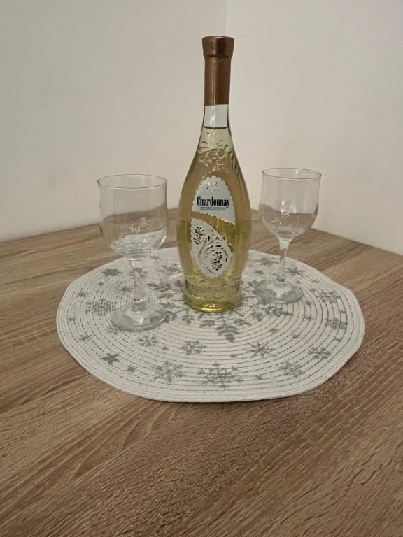 una bottiglia di vino seduta su un piatto con due bicchieri di Cute and Cozy a Pale