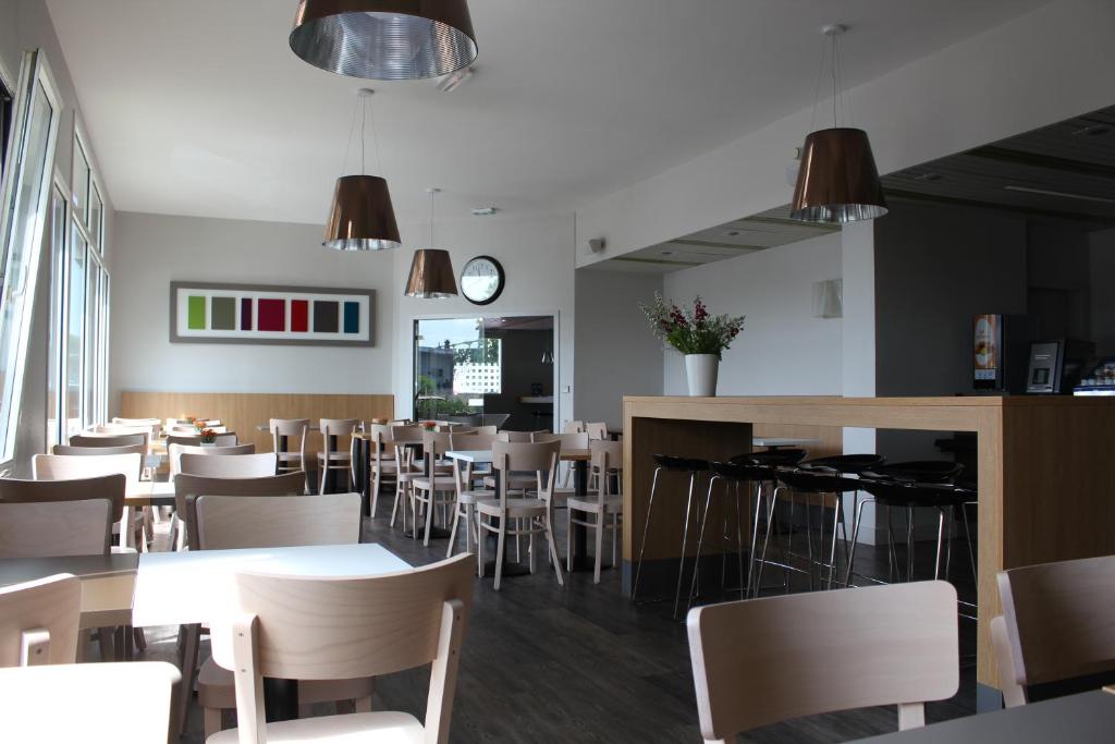 a dining room with tables and chairs and a clock at B&B HOTEL La Rochelle Centre in La Rochelle