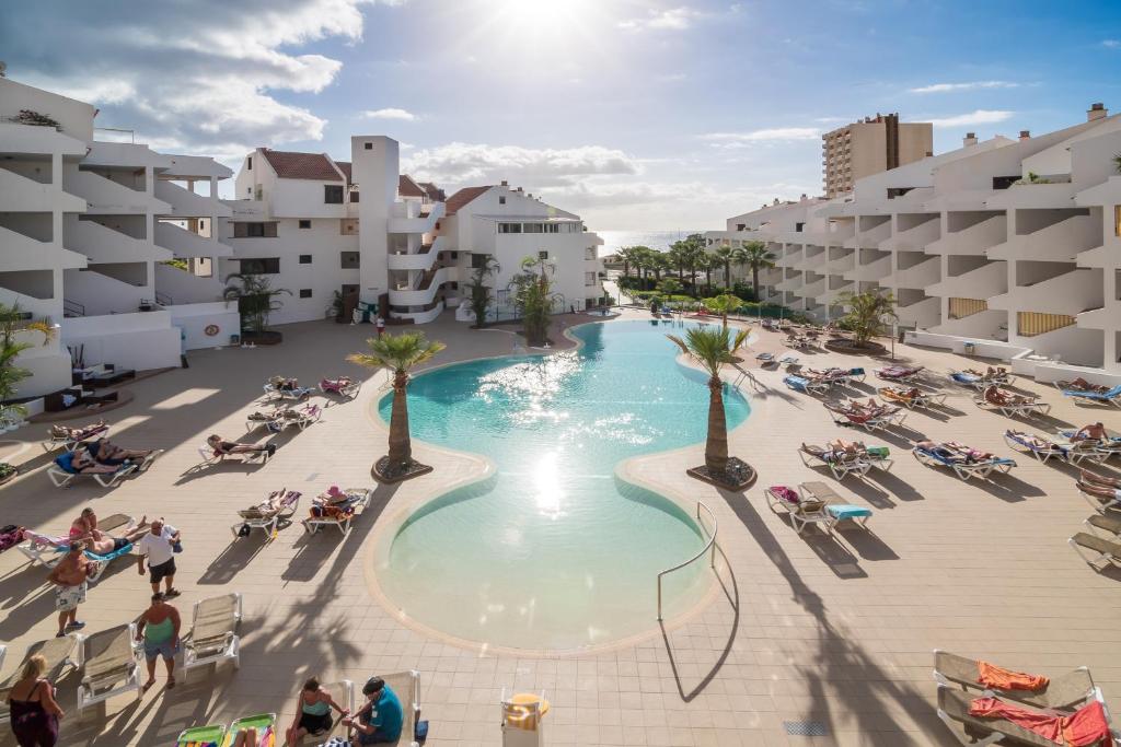 
a large swimming pool with people in it at Paloma Beach Apartments in Los Cristianos
