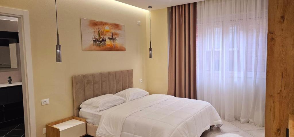 a bedroom with a white bed and a window at Sunset Harmony Apartment in Shkodër
