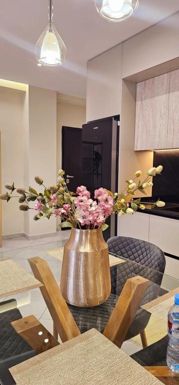 a vase with pink flowers on a table in a kitchen at Sunset Harmony Apartment in Shkodër