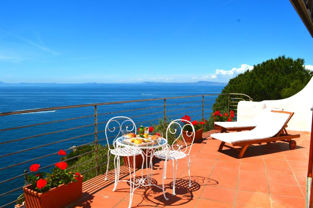 balkon ze stołem i krzesłami oraz oceanem w obiekcie Villa Oleandro w mieście Massa Lubrense