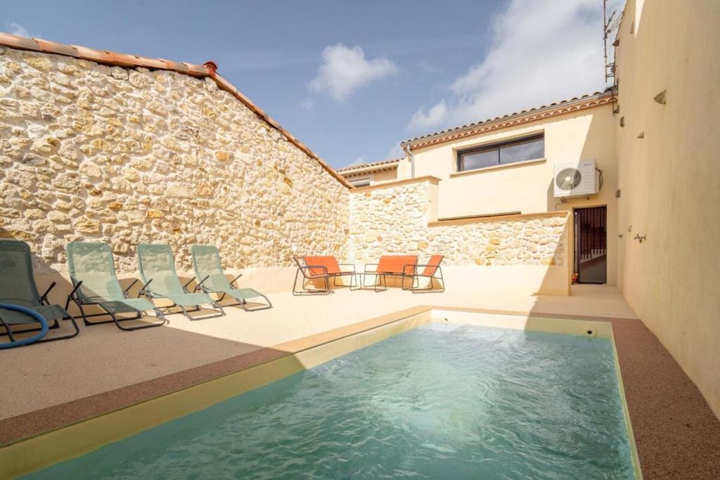 a patio with chairs and a swimming pool next to a building at Maison de charme avec Piscine-Clim-Plage à 10min in Fleury