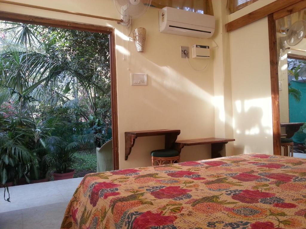 a bedroom with a bed and a large window at Michèle's Garden in Anjuna