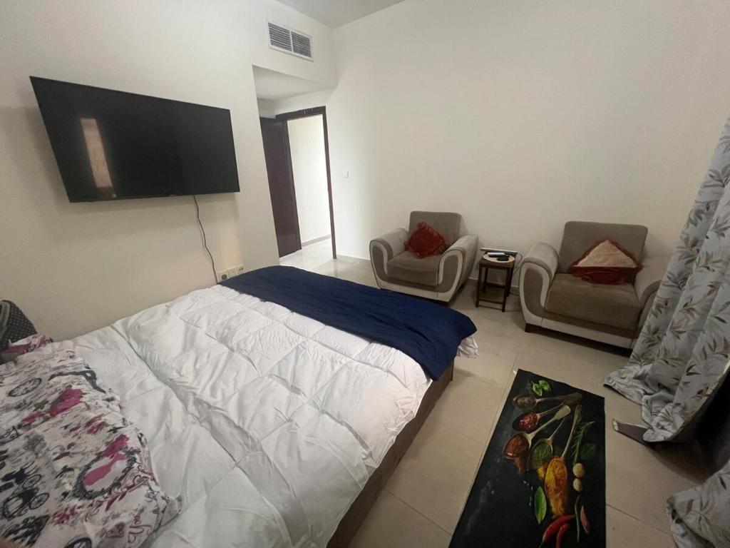 um quarto com uma cama e 2 cadeiras e uma televisão de ecrã plano em Smile Apartment Sharjah -FAMILY ONLY em Sharjah