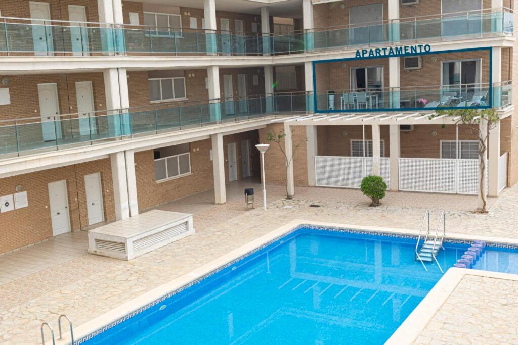 a hotel with a swimming pool in front of a building at Piso con piscina y parking in Peñíscola