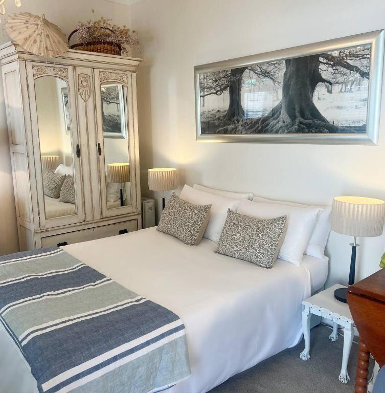 a bedroom with a white bed and a dresser at Cape Town Explorer's Rest in Meadowridge