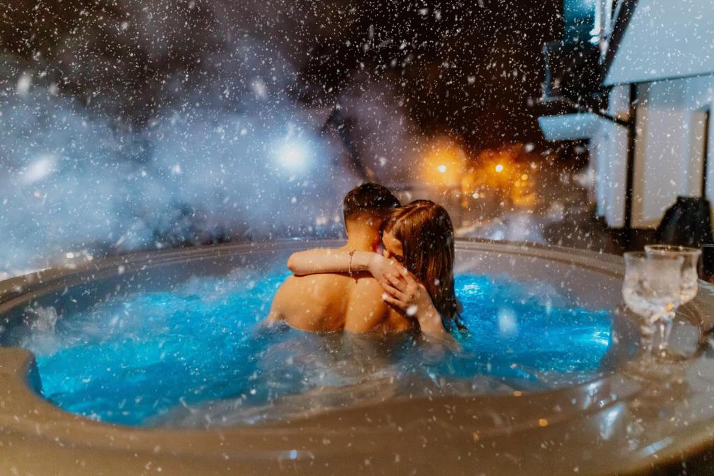 Willa Bania Rabka Zdrój - Bezpłatny całodzienny basen - blisko centrum - Widok na Babią Górę في رابكا: رجل وامرأة يجلسان في حوض استحمام ساخن