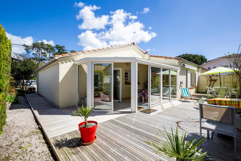 une maison avec une terrasse en bois et un patio dans l'établissement La maison du Bétey pour 4 à 5 personnes plage à 50 m, à Andernos-les-Bains