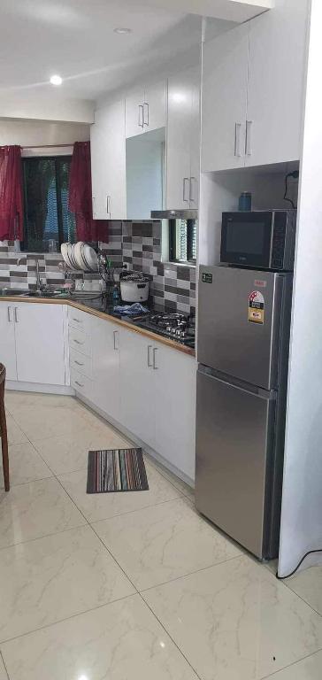 una cucina con mobili bianchi e un frigorifero in acciaio inossidabile di Alis786 Apartment a Lautoka