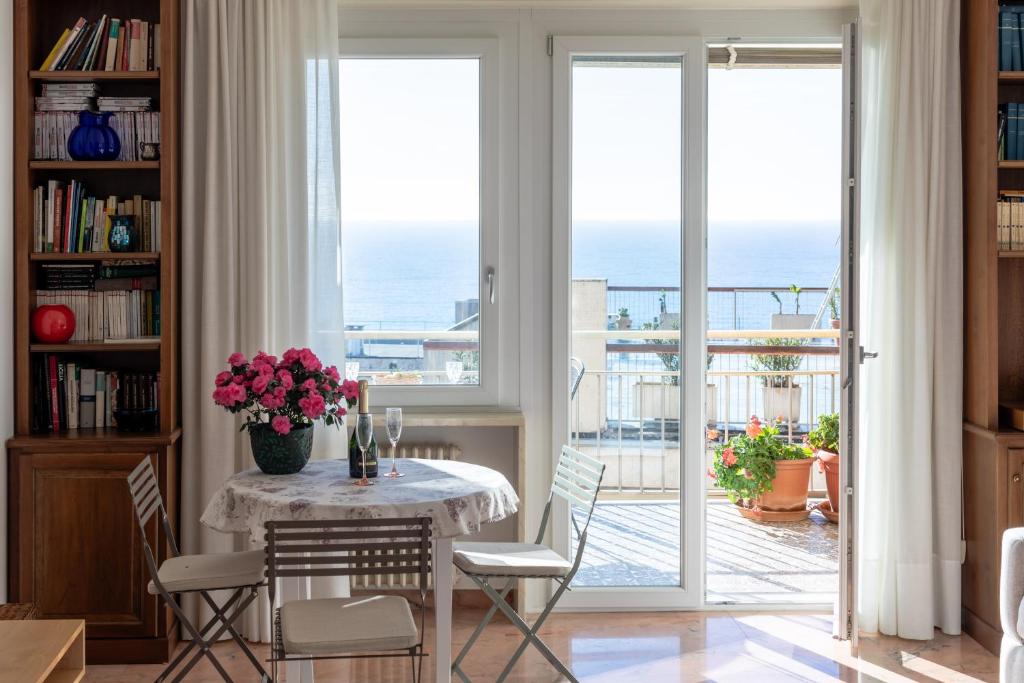 ein Esszimmer mit Tisch und Stühlen und dem Meer in der Unterkunft 282 - Casa Boscobello, Terrazzo vista Mare e Parcheggio Privato a 15 minuti a piedi dal Teatro Ariston in Sanremo