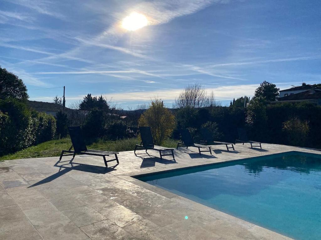 Eine Gruppe von Stühlen steht neben einem Schwimmbecken in der Unterkunft Grande maison et piscine privée in Saint-Ambroix