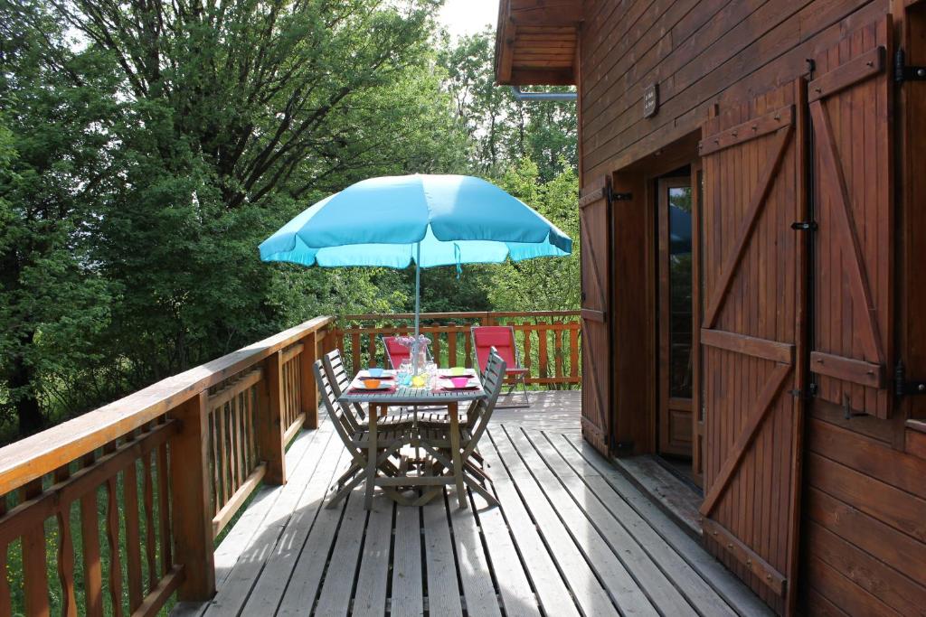 a table with a blue umbrella on a deck at Le Chalet du Berger in Briançonnet