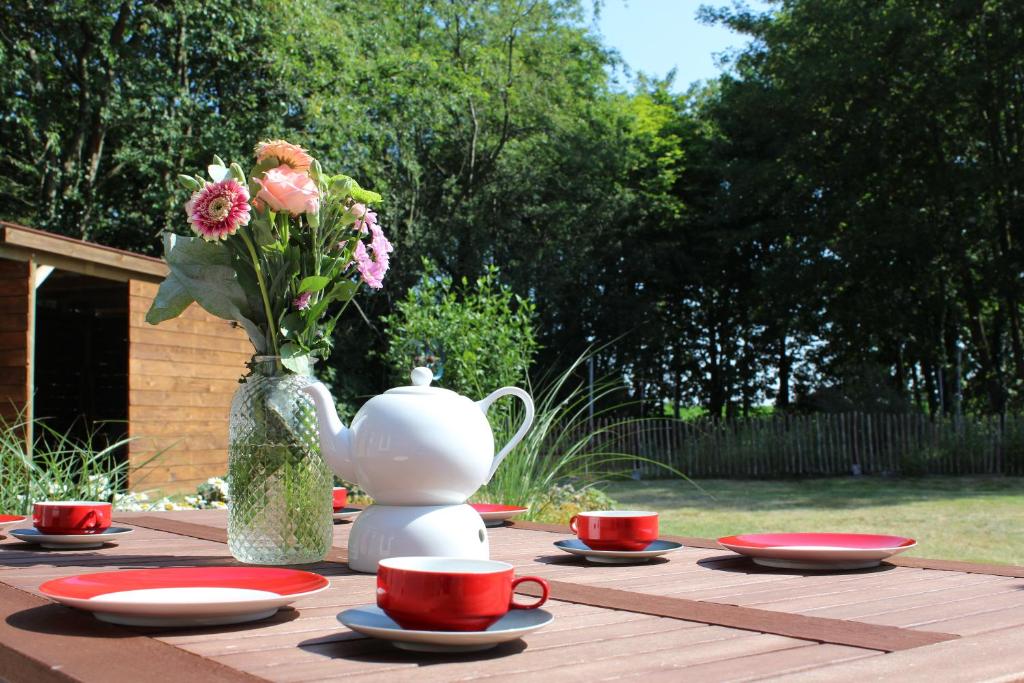ostfriesisches Ferienhaus Anno 1899 في Großheide: طاولة مع إناء من الزهور وأكواب حمراء