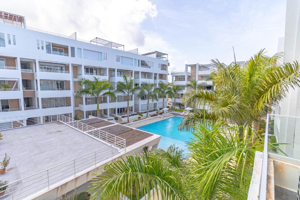 an apartment building with a swimming pool and palm trees at Beautiful Apartment 10 min from Bayahibe beach Las Terrazas in Bayahibe