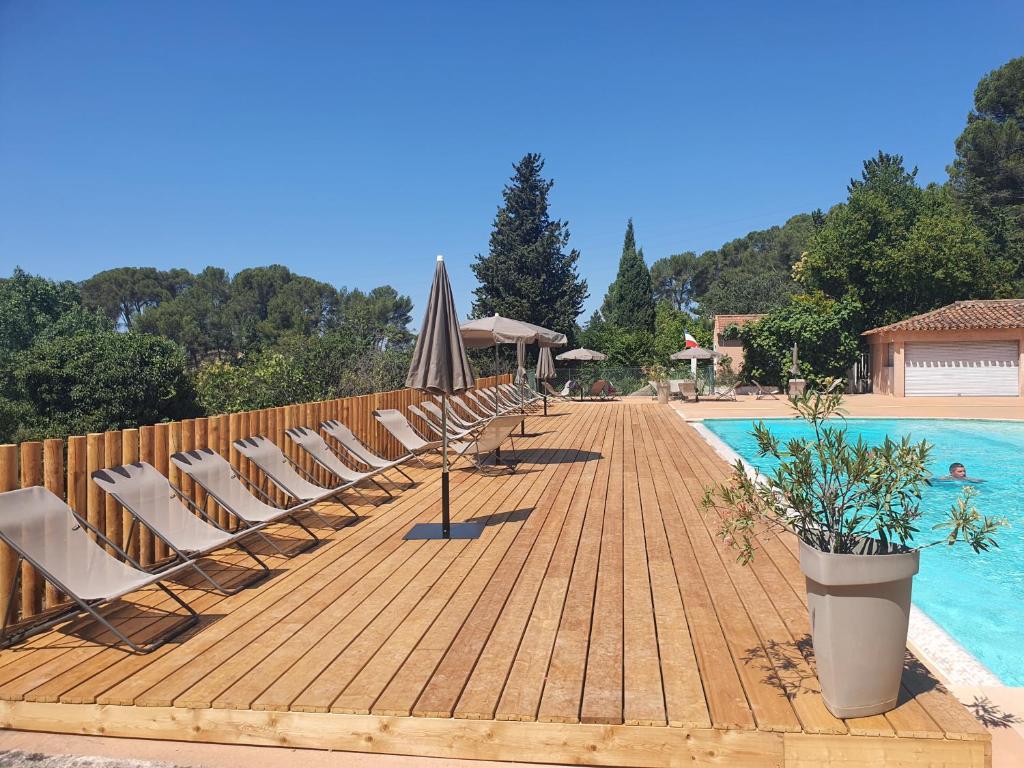 une terrasse en bois avec des chaises et une piscine dans l'établissement Citykamp d'Aix-en-Provence, à Aix-en-Provence