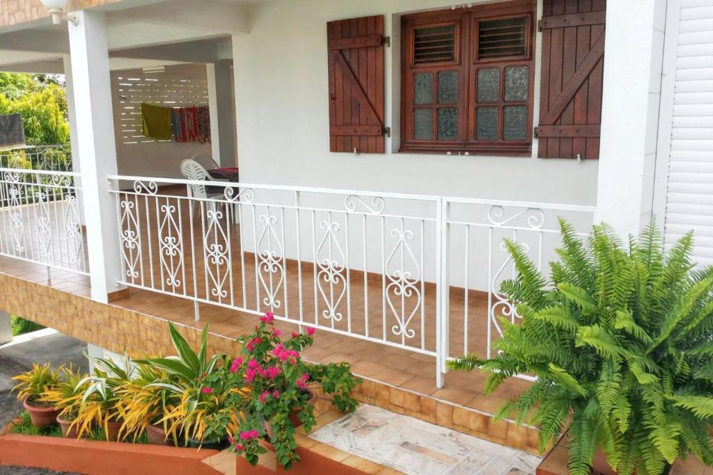 a house with a balcony with plants and flowers at Appartement confortable avec vue sur la mer à Fort-de-France - 44 m² in Fort-de-France
