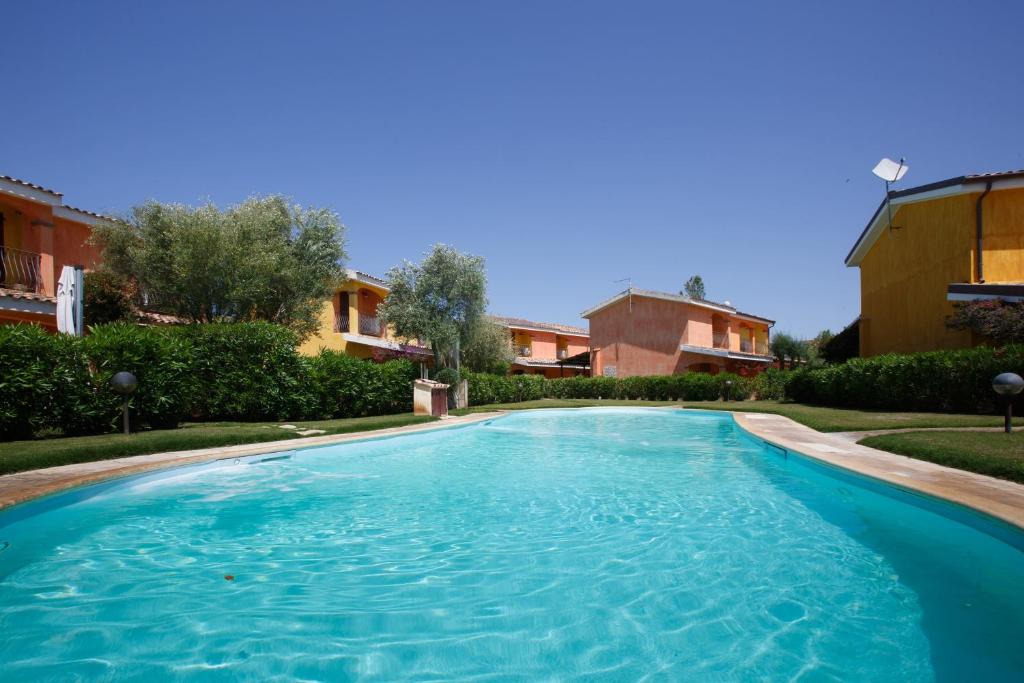 een zwembad in een tuin met huizen bij Villa Mama con piscina condominiale, giardino e barbecue in SantʼAnna Arresi