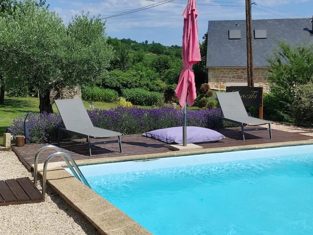 two chairs and an umbrella next to a swimming pool at Lili de La LisaThi in Cruéjouls