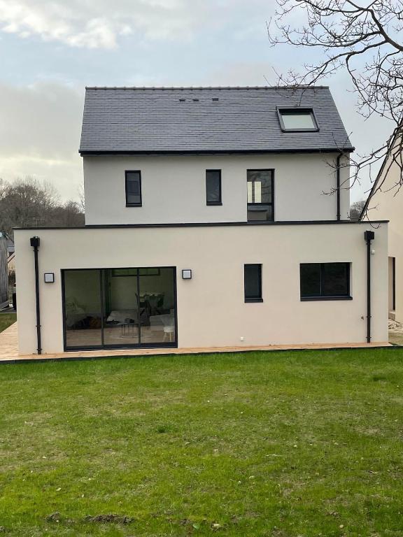 une grande maison blanche avec de grandes fenêtres sur une pelouse dans l'établissement Maison neuve mer, plage, gr 34 à pieds, à Assérac